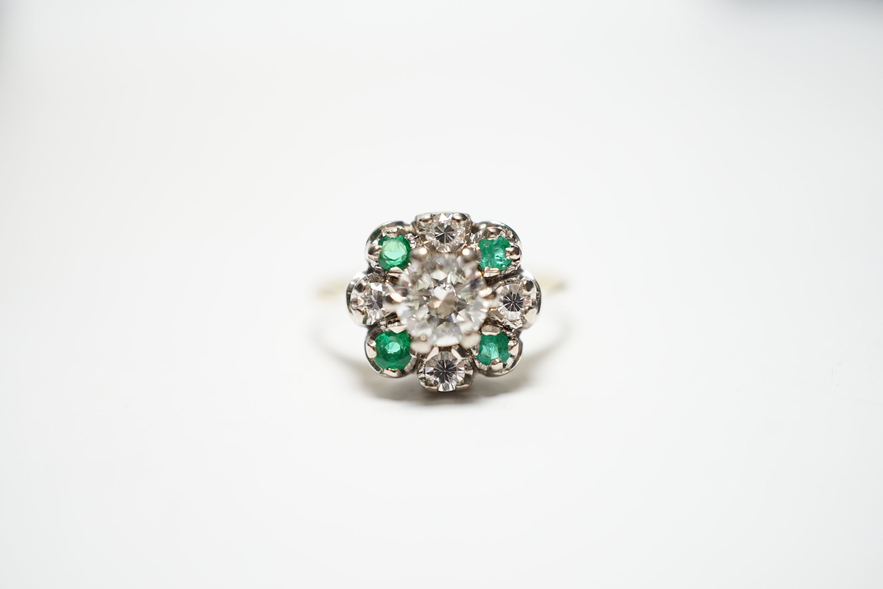 A yellow metal, diamond and emerald set flower head cluster ring, size P, gross weight 4 grams, the central diamond measuring approximately 5.5mm in diameter.